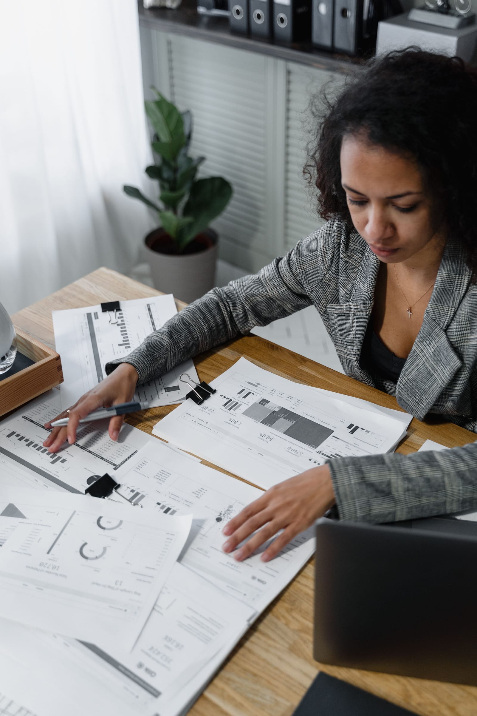 A consultant reviewing printed market data and charts spread across her desk