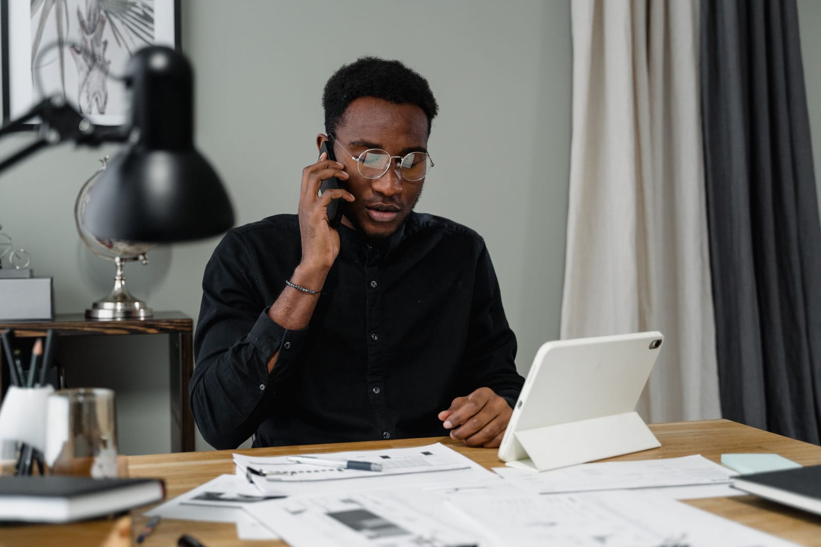 A manager fielding a work call at his desk, surrounded by papers
