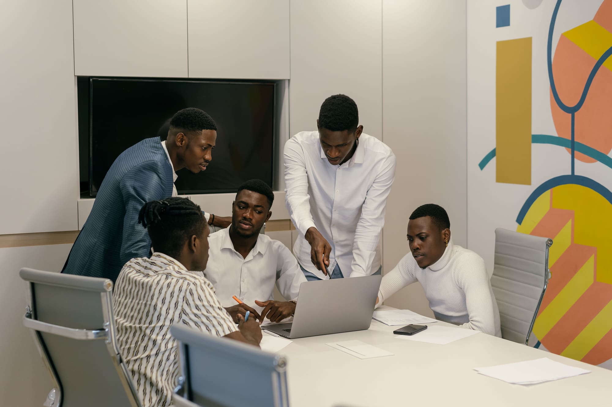 Five members of the Masy Consulting team working through a plan together around a laptop