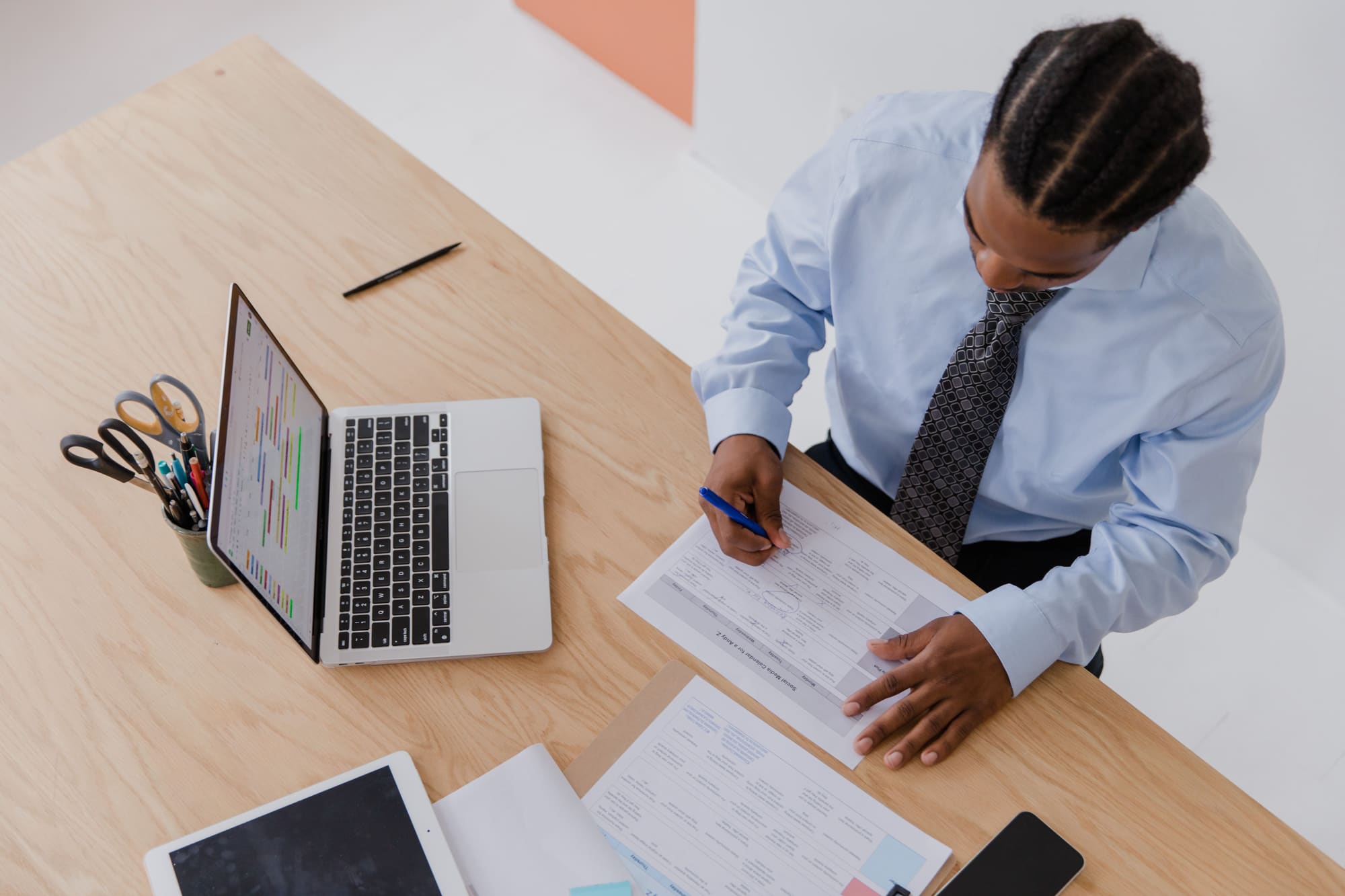 An HR manager reviewing and annotating a staff schedule at his desk
